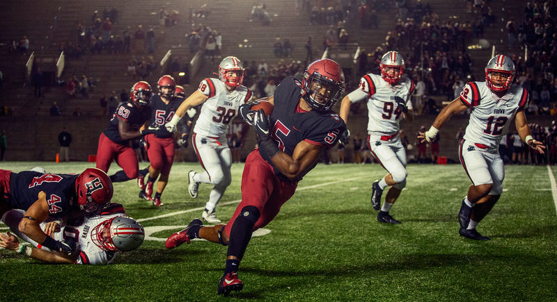 Running back breaking a tackle under the lights
