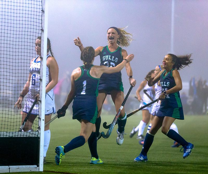 Field hockey players celebrating a goal