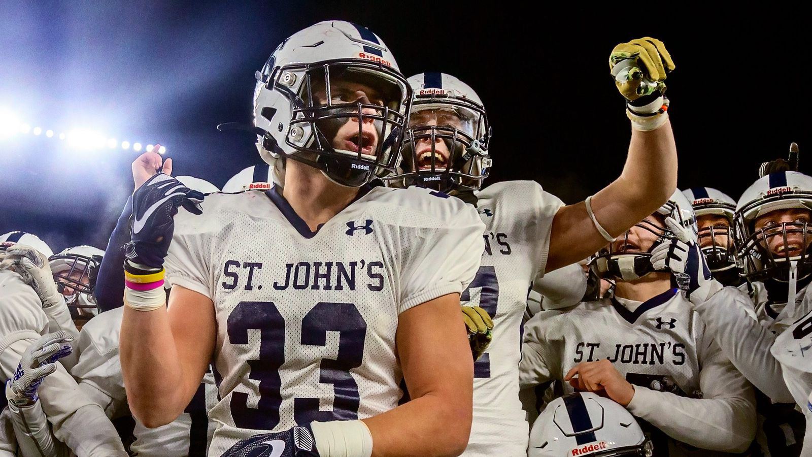 A St. John's football player in number 33 yells with his teammates under the lights